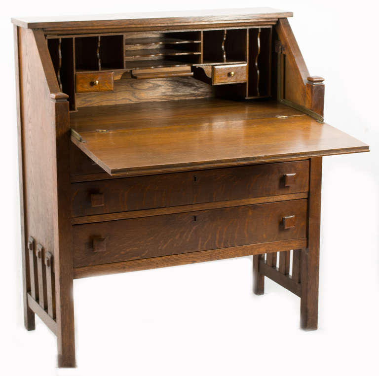 An American made solid oak, drop-front desk with three exterior drawers.