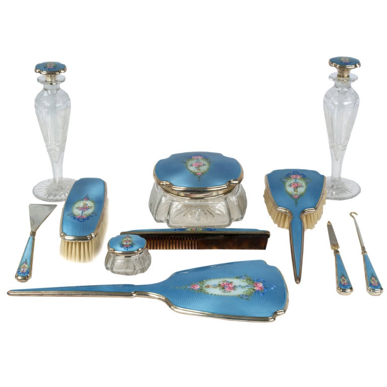 Sterling silver dresser set with rich, woven blue enamel, floral sprays, and ribbons.  This American, Art Deco set includes two perfume bottles, two brushes, a nail file, buttoner, mirror, shoe horn, and small bottle.
