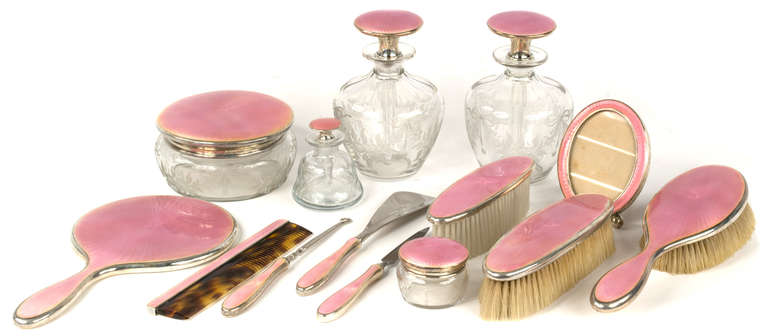 Sterling silver and enameled with rich, woven pink and floral sprays, this Art dresser set includes a picture frame, shoe Horn, three brushes, a buttoner, Horn comb, three perfume bottles, mirror, powder bottle and small bottle.