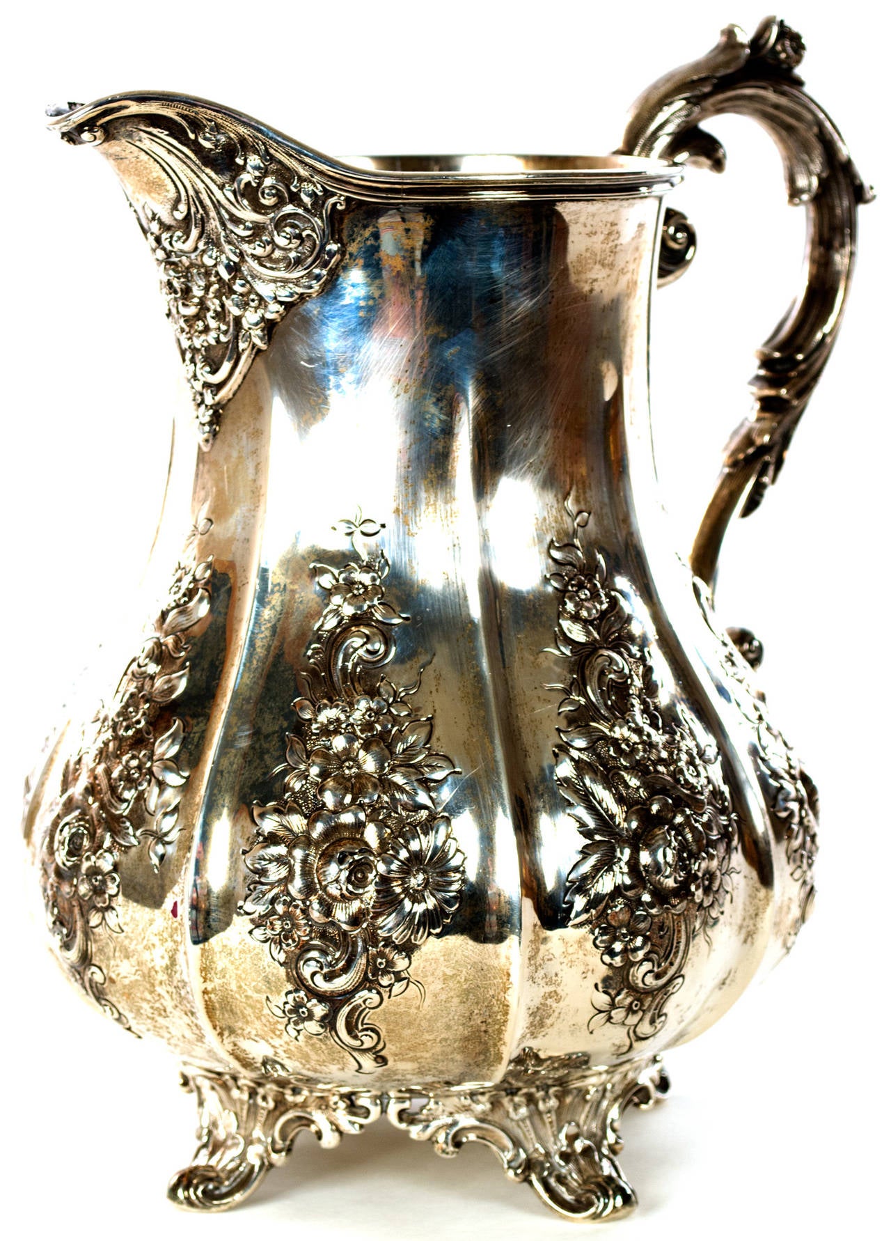 An early Tiffany and Company pitcher with Beaux-Arts-inspired shape and repoussé decorations of floral sprays on the body and a handle and feet formed by acanthus leaves, stamped 