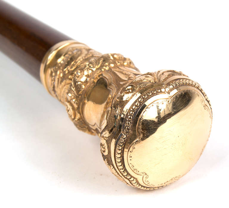 This walking stick is made with a rosewood shaft and 14k gold handle. The metal tip is enclosed in a metal ferrule.
