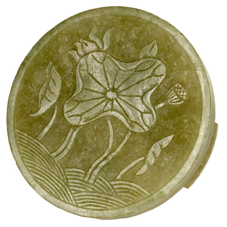 A Qing Dynasty spinach colored jade disc with low-relief carvings of poppies in fields on an elaborate carved wood stand of bats and lotus petals.