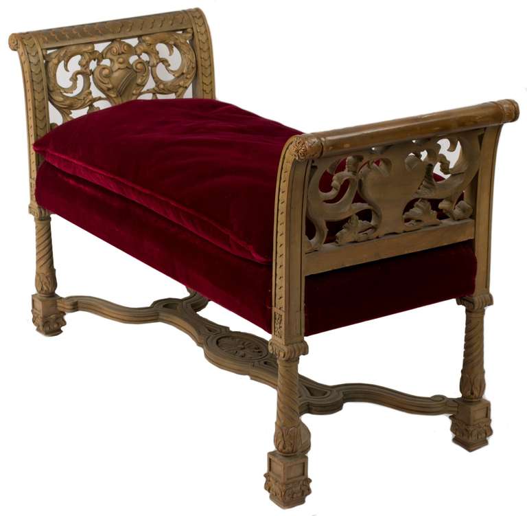 Elaborately carved with curling acanthus leaves and scales, this two seated Italian bench is upholstered with red-velvet cushions.