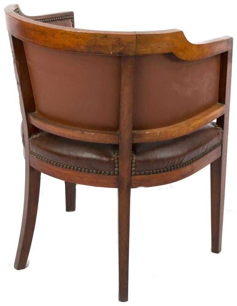 Inlaid with boxwood ribbons and neoclassical ornamentation, this leather and brass-studded leather chair, with sabered rear legs dates the the last quarter of the 19th century.