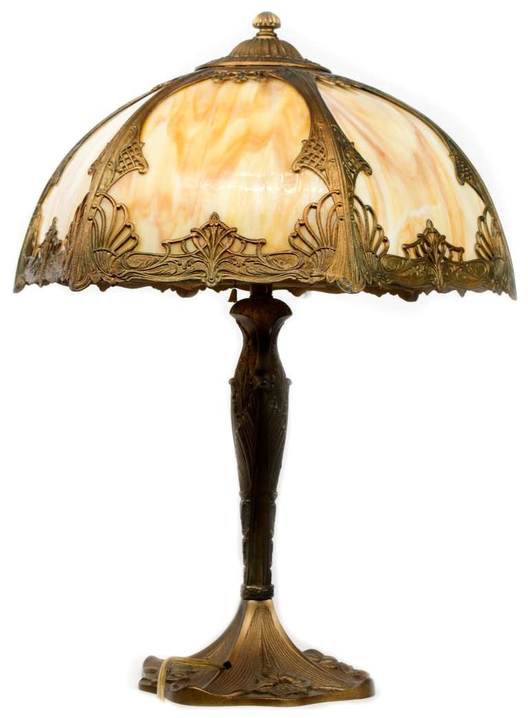 A beautifully sculpted and cold-chased bronze lamp with Art-Nouveau and Neo-classical decorative elements. The base features panels with calla lilies and the the shade, made of slag glass and bronze, is decorated with honeysuckles, vinery, and