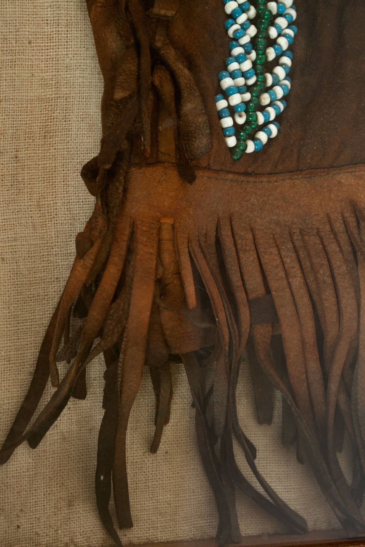 A pair of hand-made, nineteenth-century leather pants or chaps with Native American (i.e. Indian) glass bead work and holster with contemporary bullets from the American West displayed in a custom made shadowbox frame.
