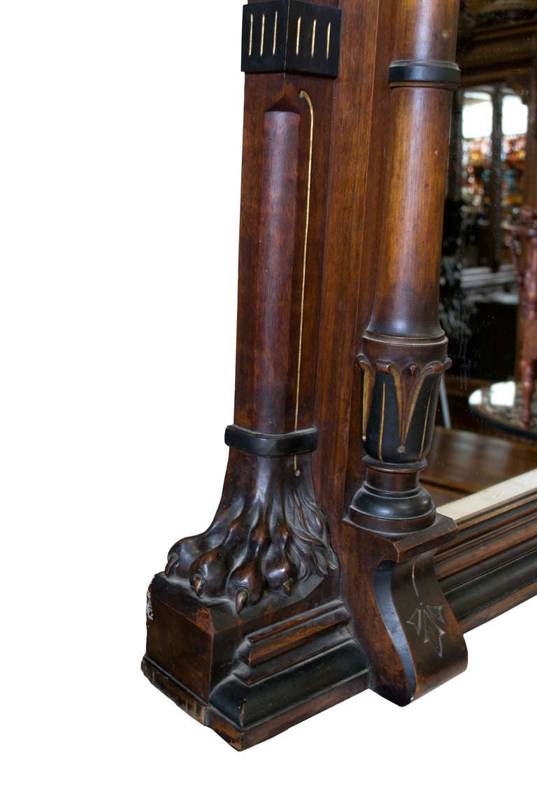 This very large mirror is veneered in beautifully preserved figured walnut, ebonized woods, and parcel gilt. The mirror is sided with carved column, each with a lion-footed base and topped with a pierced sculpture of a griffin.