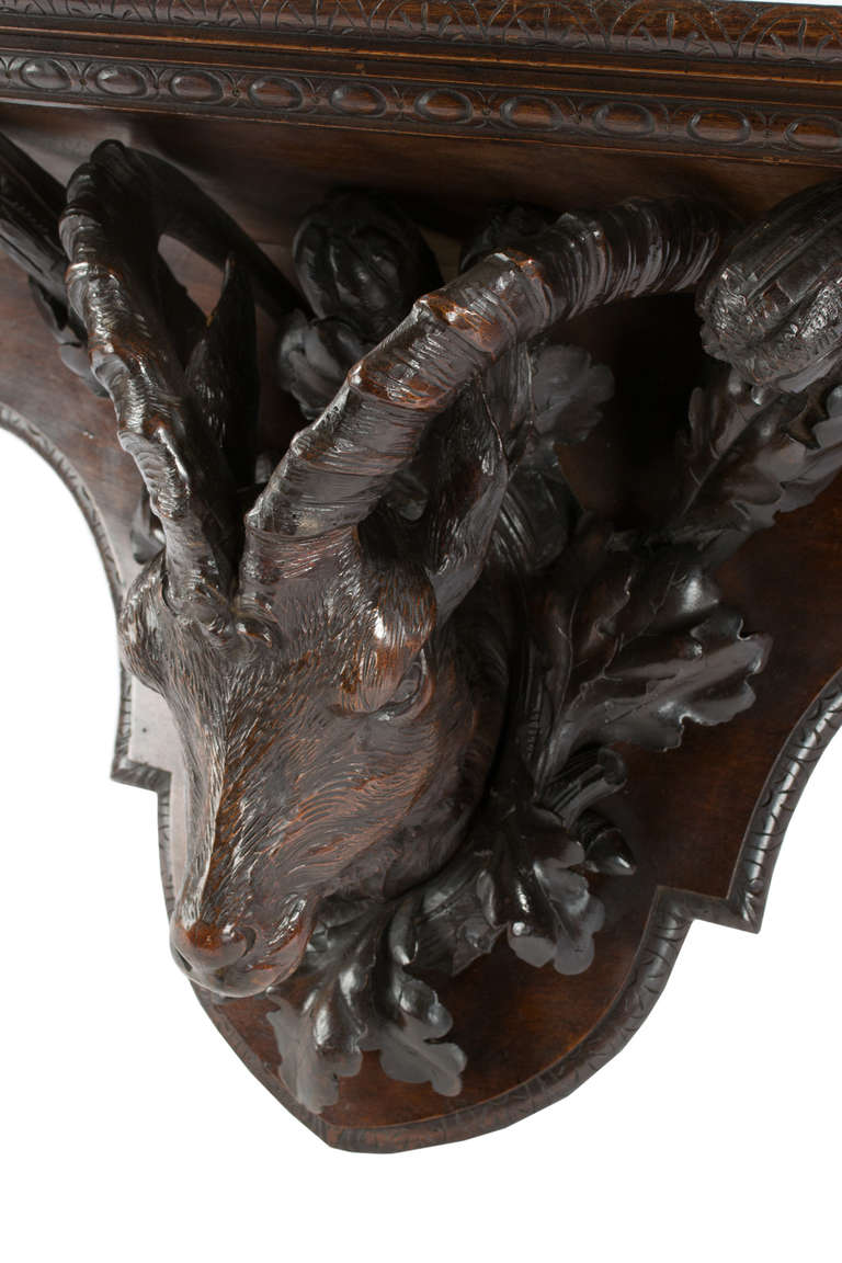 A monumental Black Forest wall shelf with full-relief carved linden wood sculpture of stag heads surrounded with foliage sprays.