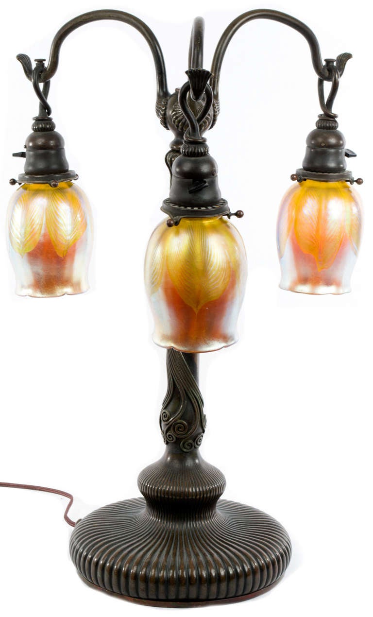 A complete Tiffany Art Nouveau lamp with three opalescent shades, each signed, a bronze, green patina body stamped 