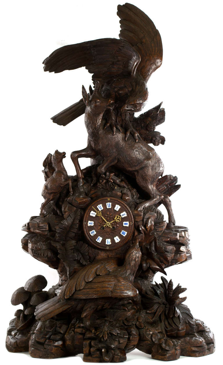 Featuring virtuosic, full-relief carvings of an eagle and stag atop the clock face and, below, birds, flowers, and toadstools, this linden wood sculptural clock is an exquisite and rare example of the best Swiss Black Forest work.