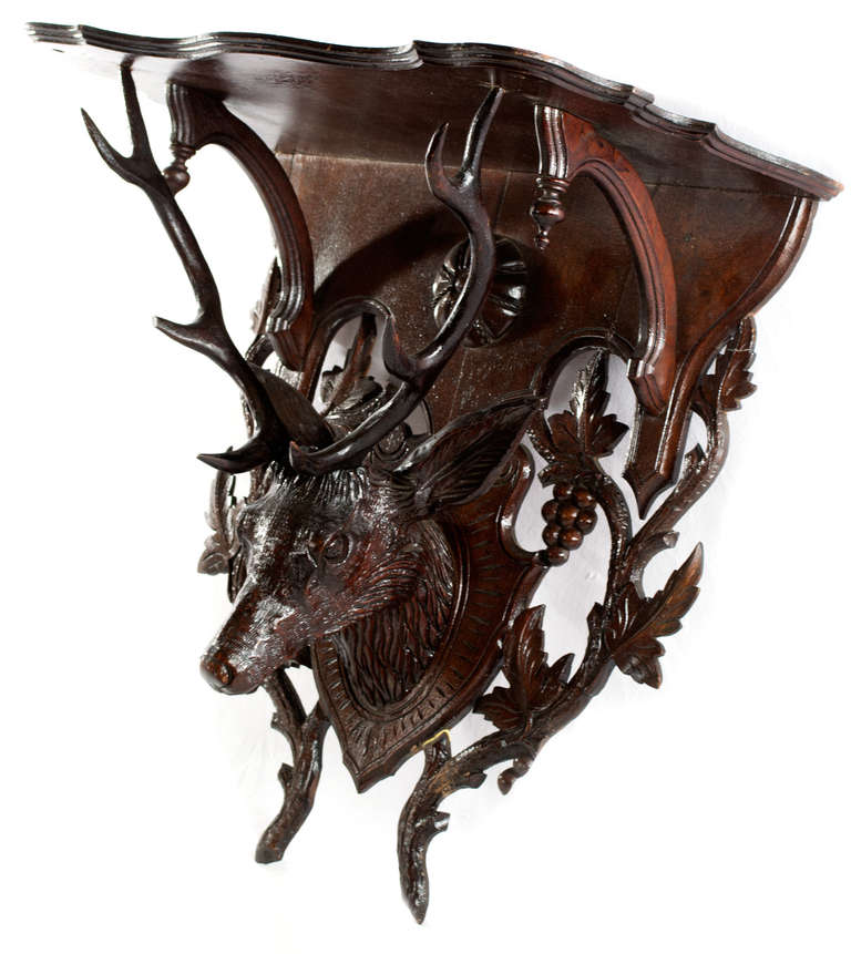A beautifully carved shelf with Gothic-Revival shaped top and large stag head with antlers, backed with pierced vinery and grape clusters.