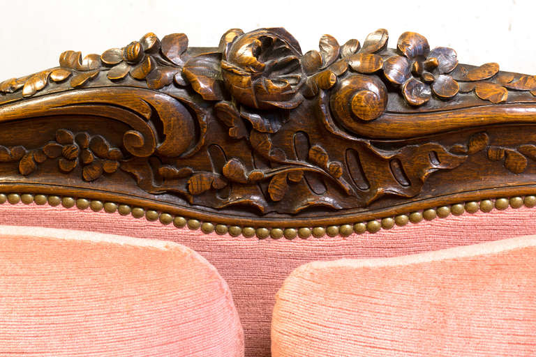 A high-backed and armed, overstuffed sofa with floral sprays and foliage carved in walnut.