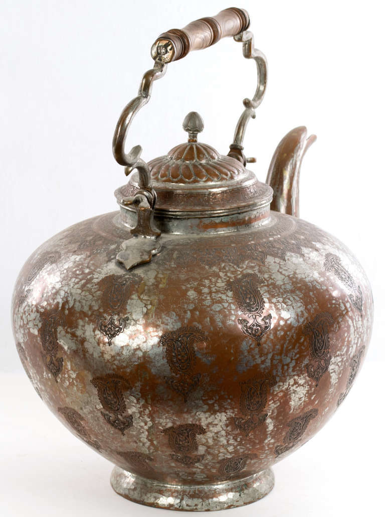 This monumental tea kettle engraved with sacred flames and topped with a hand-wrought metal and wood handle, made in India during the last quarter of the 19th century.