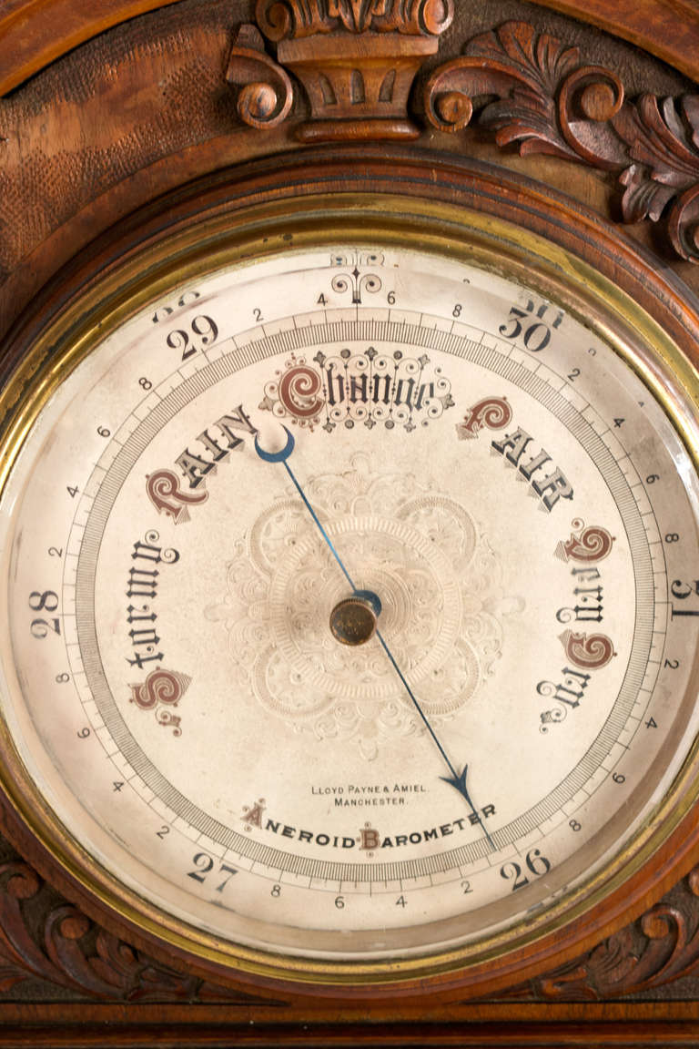 Made in Manchester during the last quarter of the 19th century, this porcelain-faced barometer and thermometer are within in a beautifully carved walnut case, featuring elaborate floral sprays, strap work, and acanthus leaves. The text reads 
