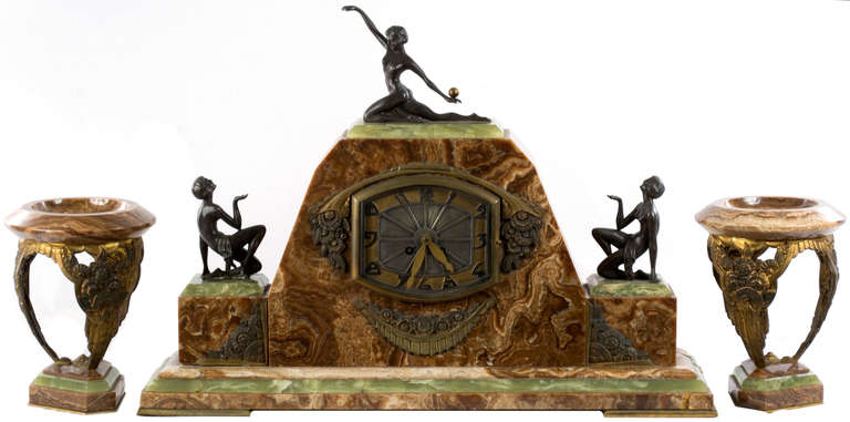 After the style of Paul Manship, this large and impressive Art-Deco  mantle clock with accompanying garnitures. The work incorporates three bronze sculptures of women — the three graces — in stylized postures. The face of the clock is surrounded by