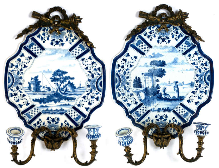 Each featuring a large, porcelain central blue-and-white panel with scenes of country life, ormolu mounts and two porcelain bobeches, these sconces were made in Holland during the first quarter of the 20th century.