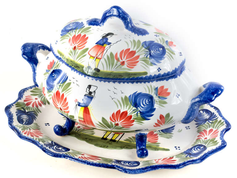 Beautifully modeled in organic Rococo forms and painted in bright, blues, greens, reds, and yellow, this tureen with matching lid and charger was made in Quimper, in the South West of France; a region famed for its dashware.