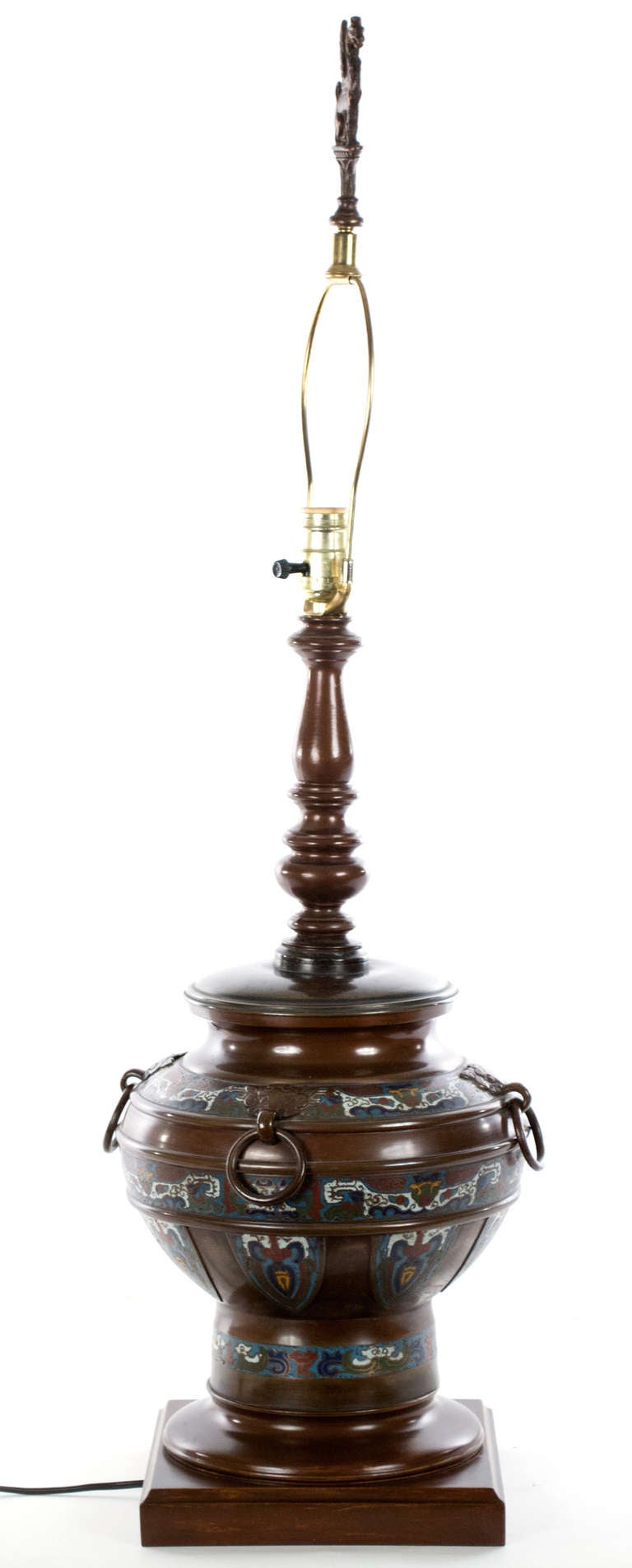 Based on the shapes of archaic Chinese temple censers, this large bronze table lamp is decorated with colorful champlevé enamel work and topped with the sculpture of a dragon.