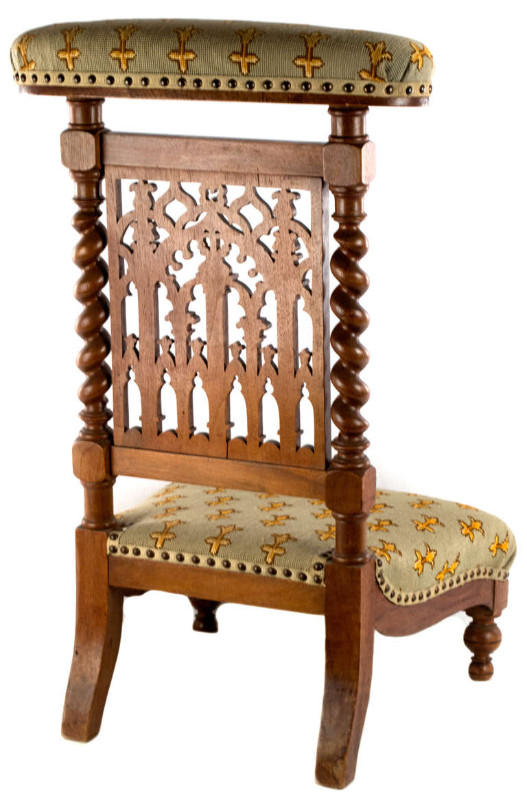With the back beautifully made with blind carvings of gothic ogee arches and columns, sided by Portuguese-turning (a.k.a. Solomonic columns), the seat and arm rest of this kneeling prayer chair are covered with needlepoint fleur de lis combined with