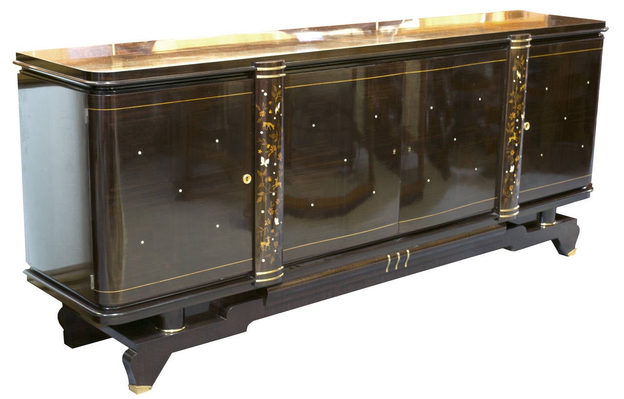 A complete French Art Deco dining suite in ebony and fruit woods, inlaid with mother of pearl, boxwood, and brass based on the style of Jules Leleu and made in France during the second quarter of the nineteenth century. The suite includes eight