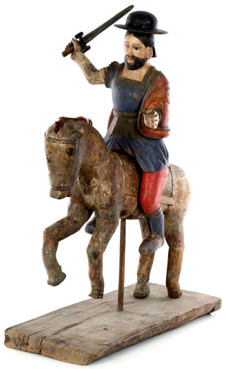 A Spanish colonial gilt and polychromed sculpture of a santos (i.e. religious figure) on horseback and wielding a sword, mounted on a stand and made in Mexico during the late nineteenth century. Santiago Matamoros is said to have appeared during the