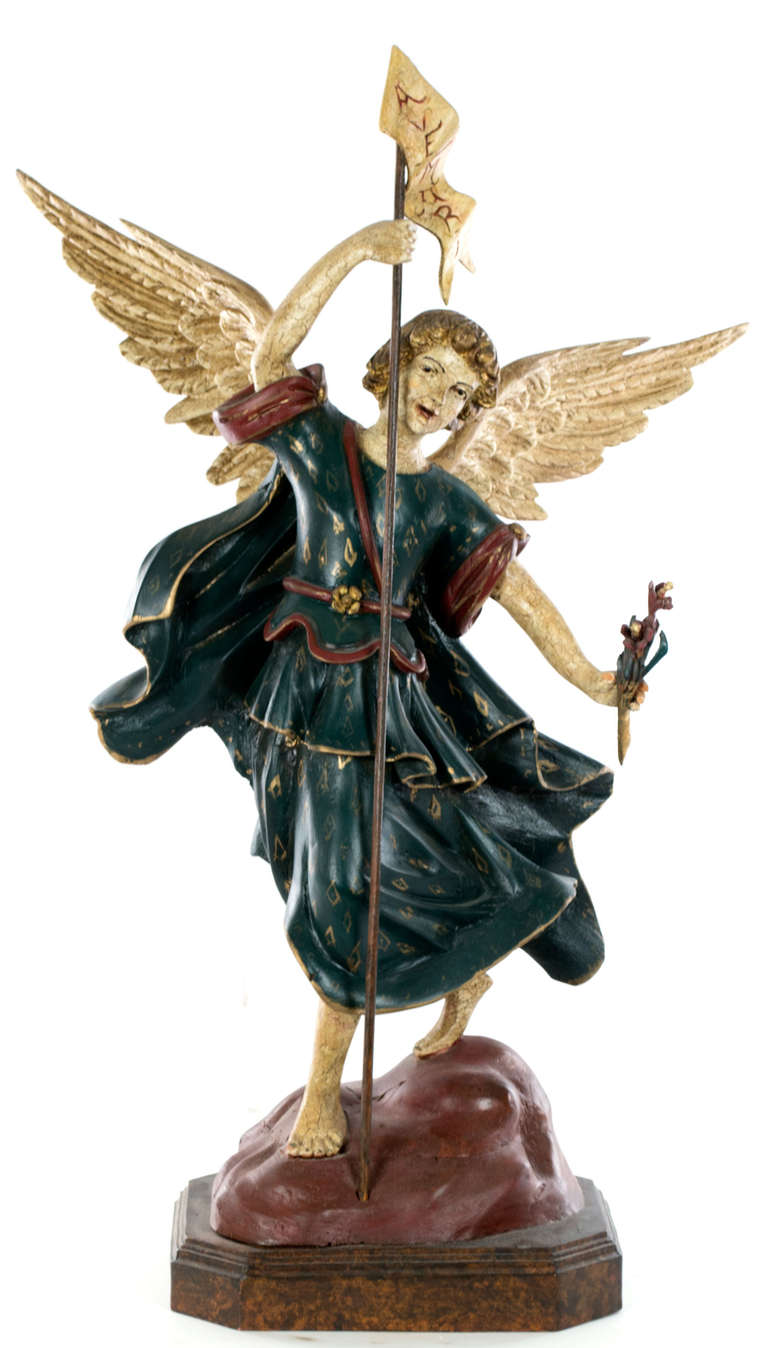 Two large Spanish Colonial statues depict the Archangel Michael, the first showing him triumphant over the devil and the other carrying the message of victory. The figures are beautifully realized, with large, life-like wings and carefully