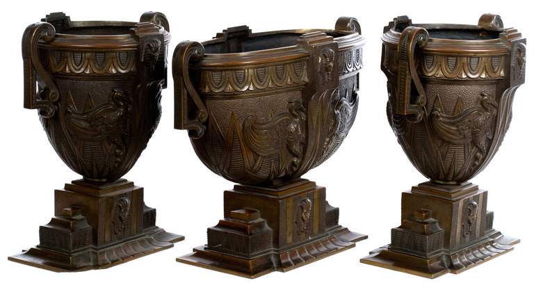 Three very heavy bronze vases with handles and each featuring beautiful, carefully chased low relief carvings of Egyptian pharaohs, sacred herons, and architectural elements.