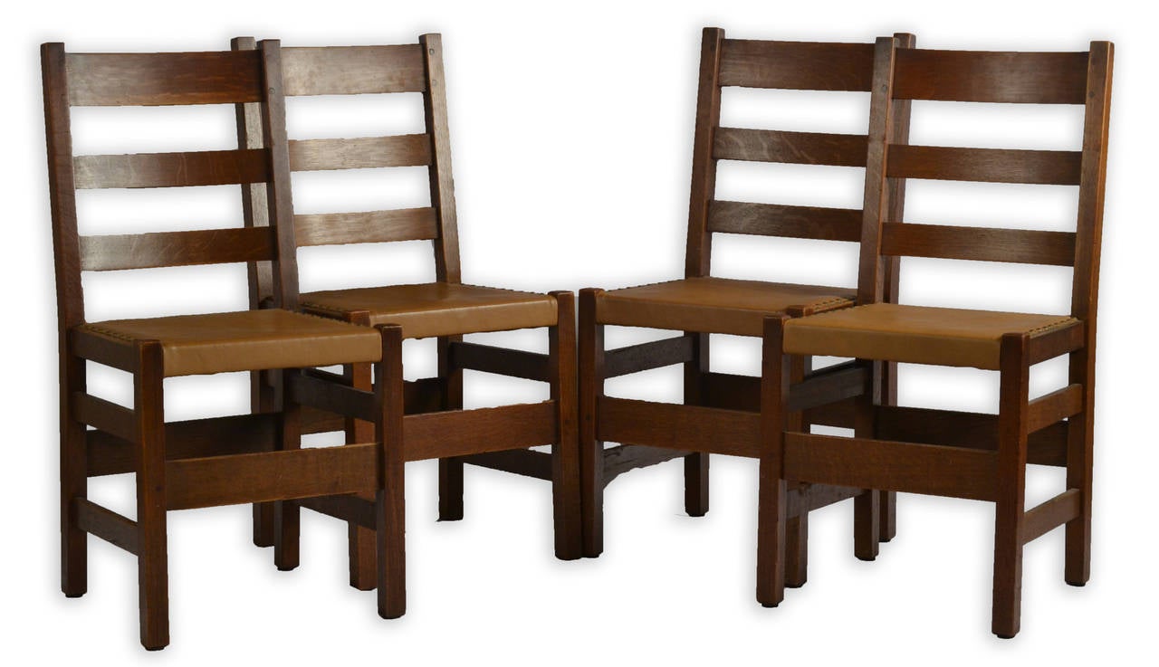 Eight oak slatted side chairs with leather seats by the American furniture maker L. & J. G. Stickley.
