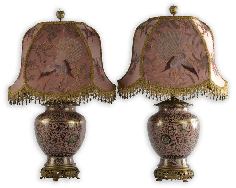 This pair of cloisonné lamped vases is topped with fanciful cloisonné and brass apple finials, and feature carefully embroidered and jeweled silk lamp shades.