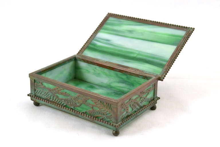 A slag glass and bronze desk box made by Tiffany and studios featuring the grapevine motif.