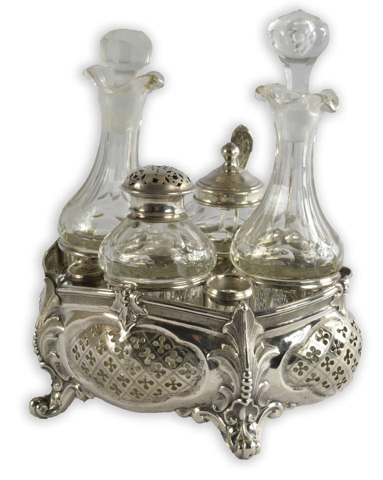 A cut glass and sterling silver set with bottle for perfume, talc, and accoutrements for a lady's toilette. The fine work in silver features pierced quatrefoils, acanthus leaves and raised feet.