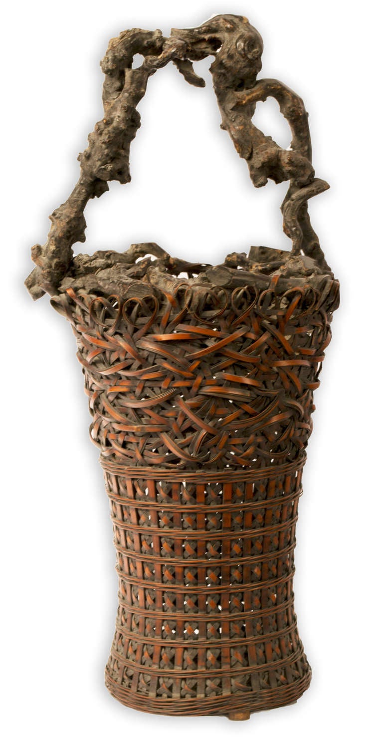 This nineteenth-century Japanese bamboo and burl wood basket represents the highest tradition of Japanese craftsmanship of Ikebana, Japanese flower arranging. The basket integrates a burl wood handle with woven and plaited bamboo.