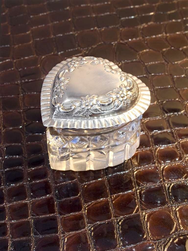 Perfect for keeping treasured trinkets in, this cut glass heart shaped box has an intricate silver plate lid.