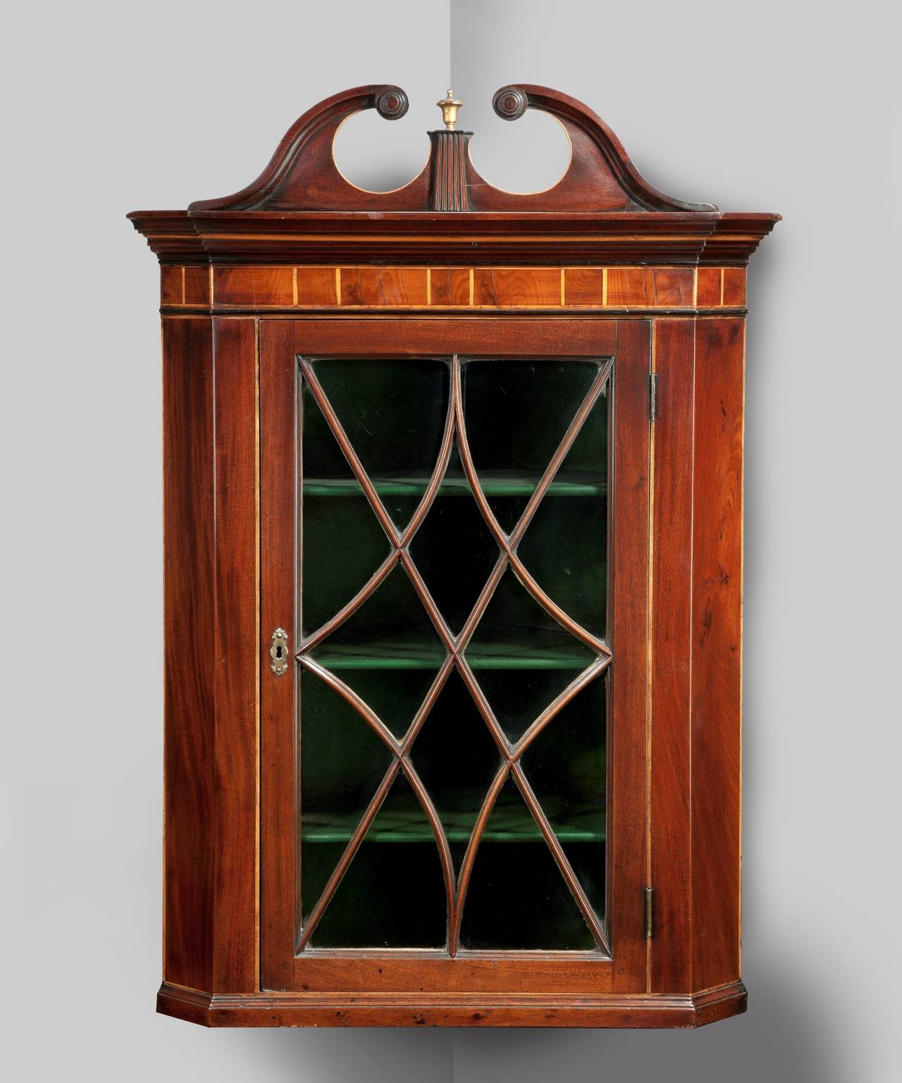 A George III Sheraton period mahogany hanging corner cupboard; the swan neck pediment above a boxwood strung cornice; the glazed door with an elegant astragal. 

For more information on the Sheraton period please read this article on our blog.