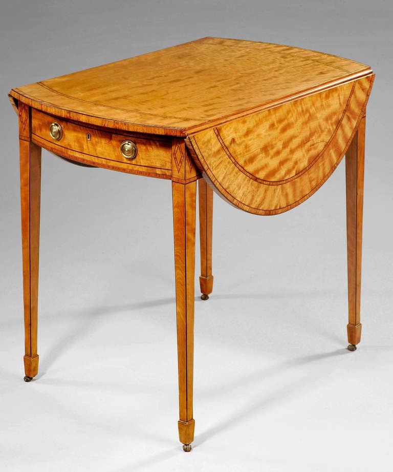 A Sheraton period satinwood oval pembroke table; the well figured top is double banded in tulipwood; standing on elegantly drawn square tapering legs. 

THOMAS SHERATON (c.1751-1806)