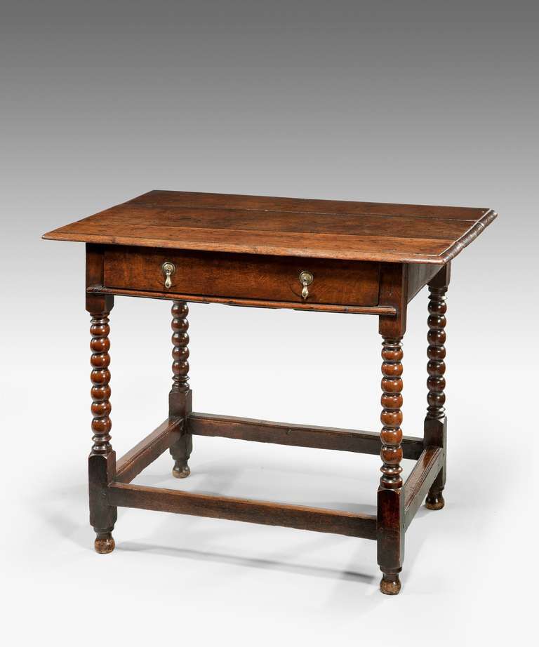 A late 17th Century oak one drawer side table; the plank top above a frieze drawer and raised on ball turned legs united by stretchers.