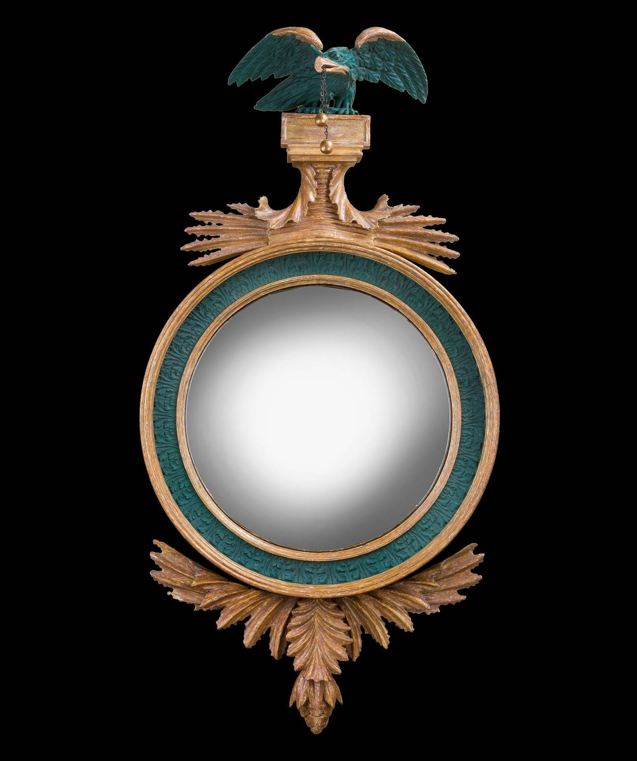 A Regency period carved giltwood and bronzed convex mirror; the mirror plate set within a reeded and acanthus carved frame surmounted by an eagle above an acanthus spray and with a crisply carved acanthus leaf apron.

Bearing a label to the