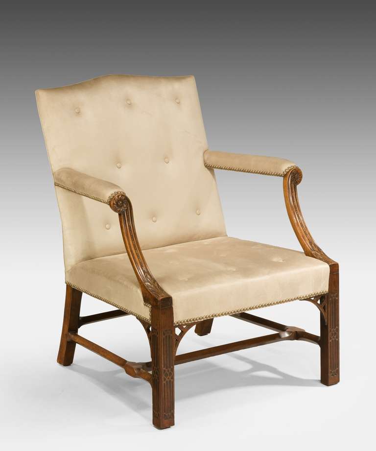 A fine George III Chippendale period mahogany Gainsborough armchair; the camel back above downswept arms carved with acanthus leaves and a patera, raised on square chamfered legs decorated with gothic blind fretwork and united by an H stretcher.
