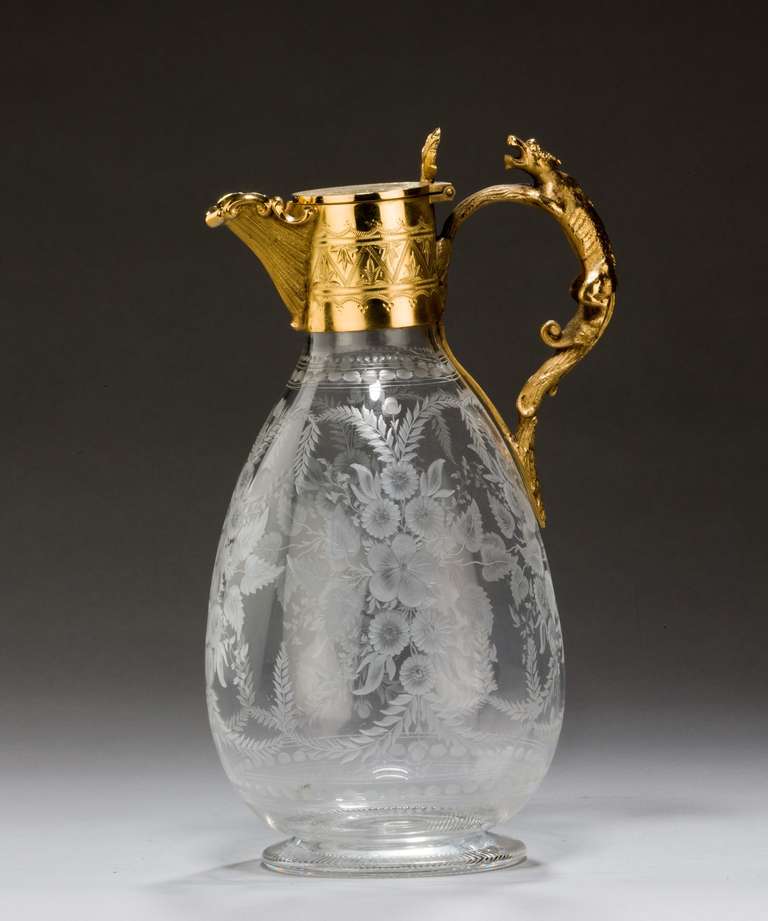 A late 19th century claret jug with hand engraved glass and gilt metal mounts.