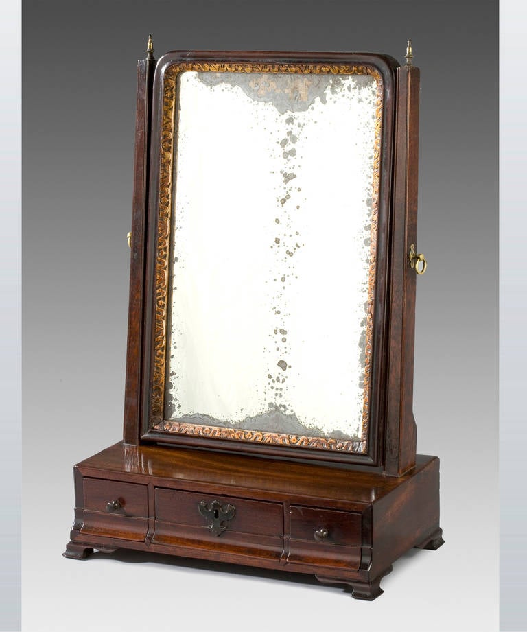 A fine George II period mahogany dressing mirror; having 3 frieze drawers with stepped fronts and standing on ogee bracket feet.