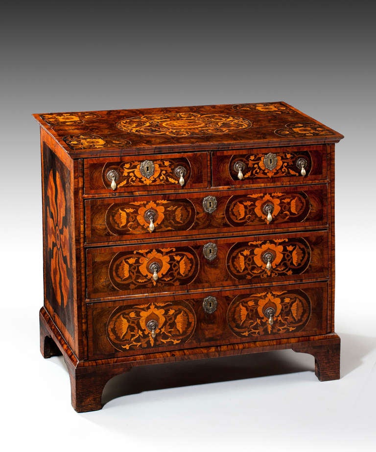 A rare William and Mary oyster veneered and marquetry inlaid chest of drawers; the top veneered in oysters of olivewood and crossbanded in olivewood inlaid to the centre with a marquetry panel of flowers surrounding a parrot and with marquetry