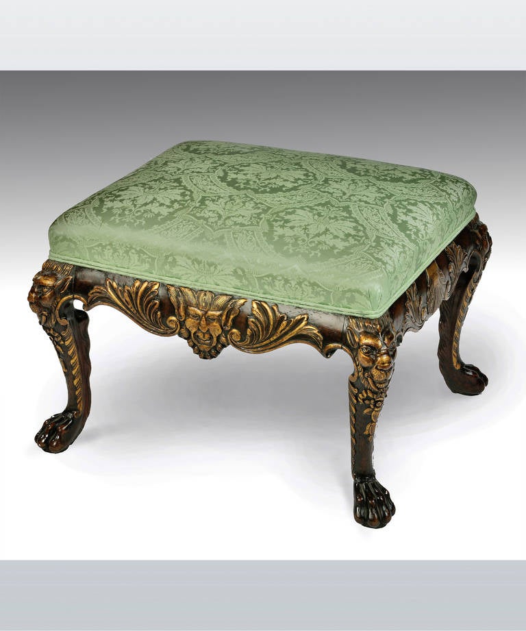 A George I style carved walnut and parcel gilt stool; with satyr masks to the centre of the frieze and standing on cabriole legs which terminate in claw and ball feet.