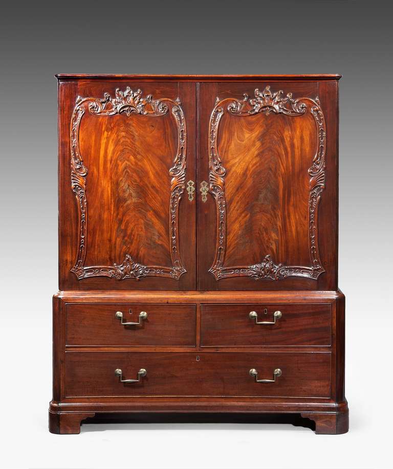 A rare George III Chippendale period carved mahogany cabinet; the cabinet's cleated top above a pair of cupboard doors which are veneerd with panels of Cuban curl mahogany framed within a vigorously carved border of C scrolls incorporating acanthus