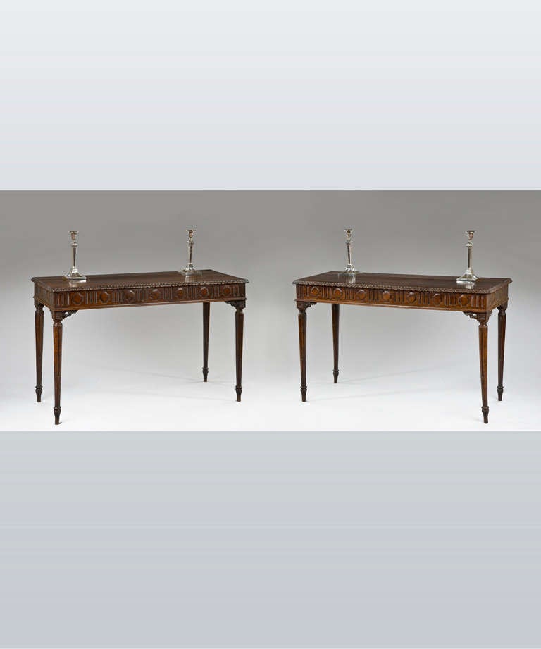 A pair of late 18th Century North Italian carved chestnut console tables; the tops with a running acanthus moulding to the edge above a geometrically carved frieze and raise on elegant stop fluted legs.