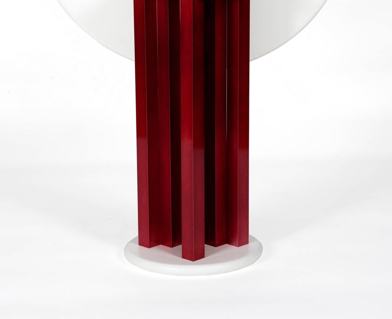 Sculptural center table with a white top surface and base. The elements in central supporting column are lacquered in red | The top surface is hinged and can be positioned vertically to be stored away.