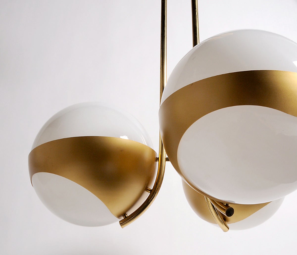 Suspension light with three glass opaline globes resting on a metal frame.
