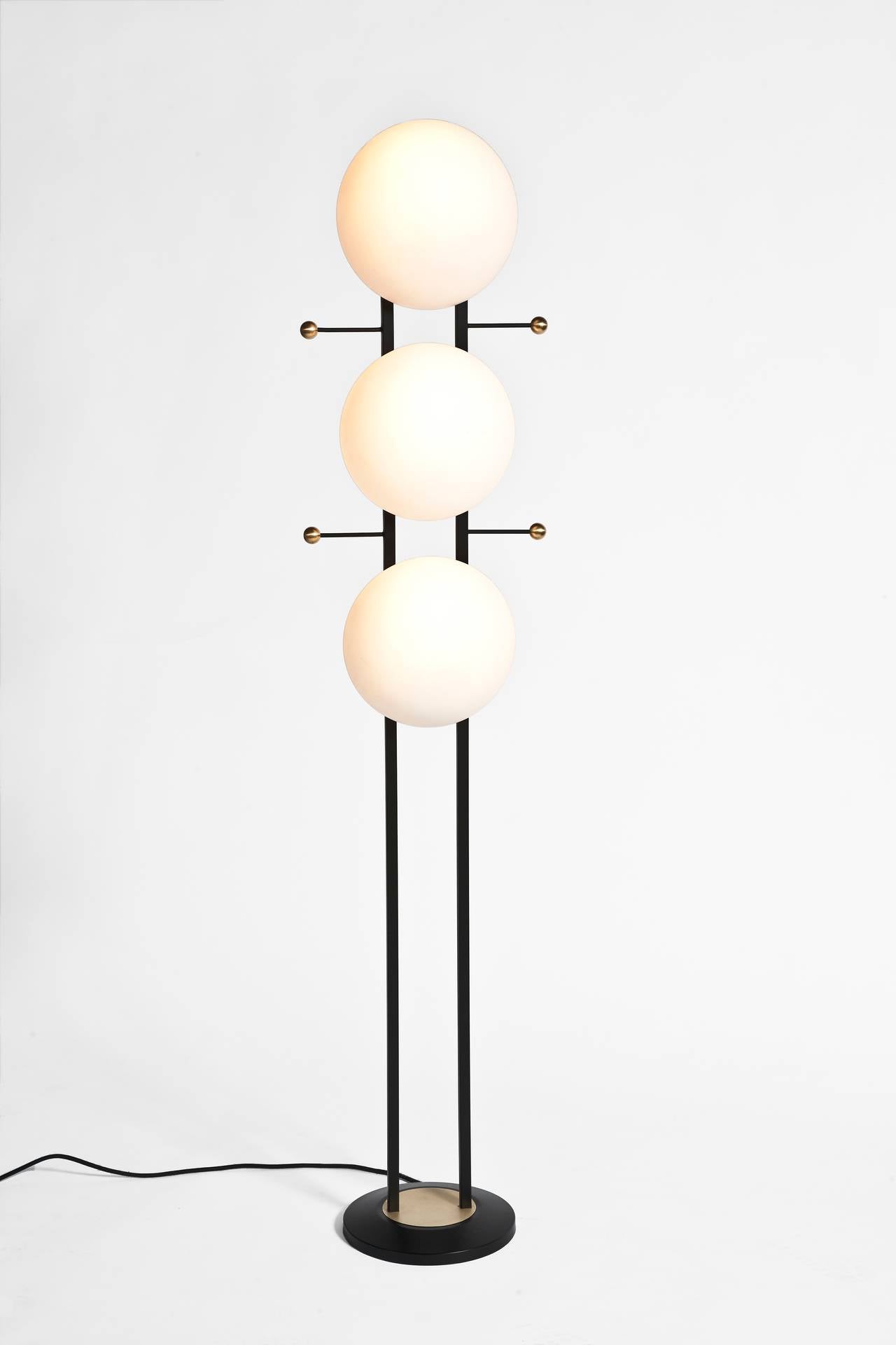 A 1950s floor lamp with three opaline glass shades, black and brass metal.