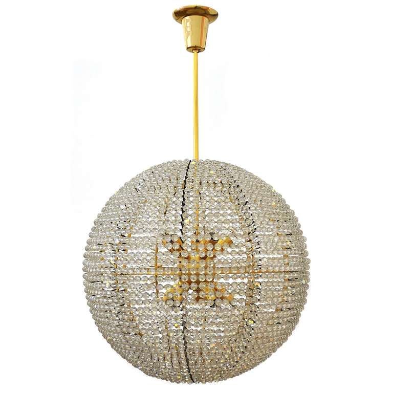 This lovely Austrian chandelier, manufactured around 1960, takes form of a ball and has 10 lightbulb sockets. The brass frame is partially gilded in high quality. Strings of cut crystal balls, held in place by the many bridges, are wound