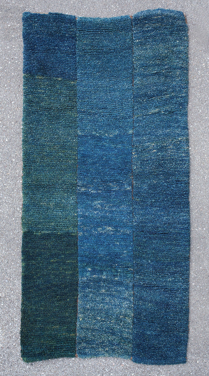 This antique geometric Tibetan Tsukdruk has a reduced Minimalist design. 

Made in three narrow strips joined together, this rug’s unique design is created by the vivid abrash, the color variations ranging from light blue to dark green. The