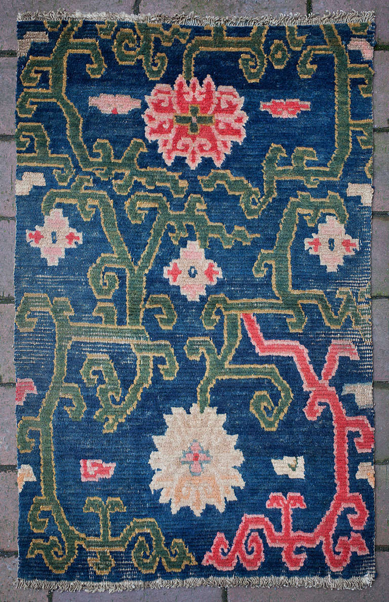 This charming Tibetan sitting rug features a design of scrolling vines with lotus and diamond flowers.
Originally made as a sitting rug, this little Khagangma was most likely used on top of a saddle. The indigo blue background is decorated with